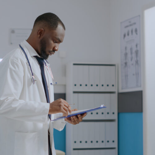 African american specialist doctor checking sickness report documents analyzing medical expertise Sports Physicals